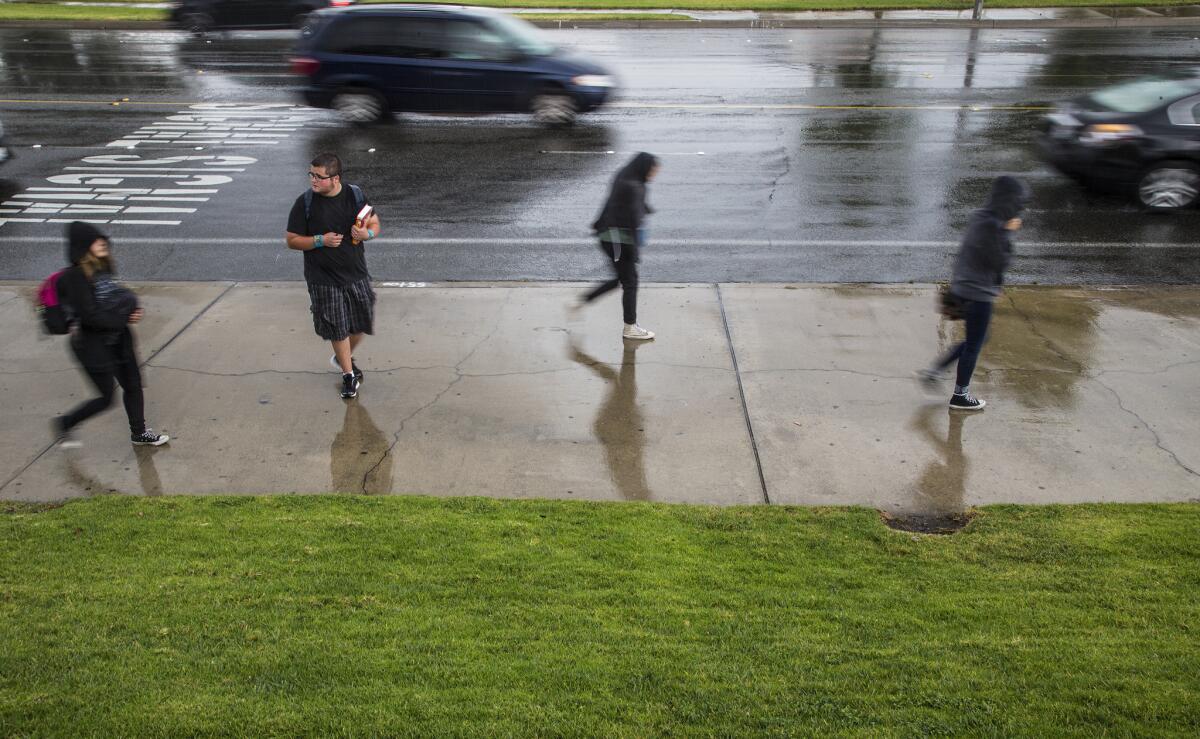 Alta Loma High School students get caught in a rain storm as they leave school on Friday in Rancho Cucamonga. Thunderstorms could strike the region Saturday.