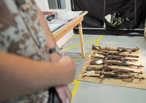 A Danish navy sailor stands guard as confiscated weapons from Somali suspected pirates go on display