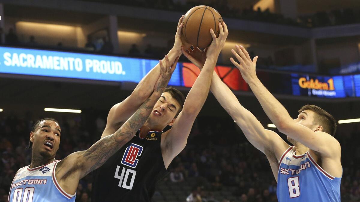 Clippers center Ivica Zubac grabs a rebound between the Sacramento Kings' Willie Cauley-Stein, left, and Bogdan Bogdanovic during the first quarter.