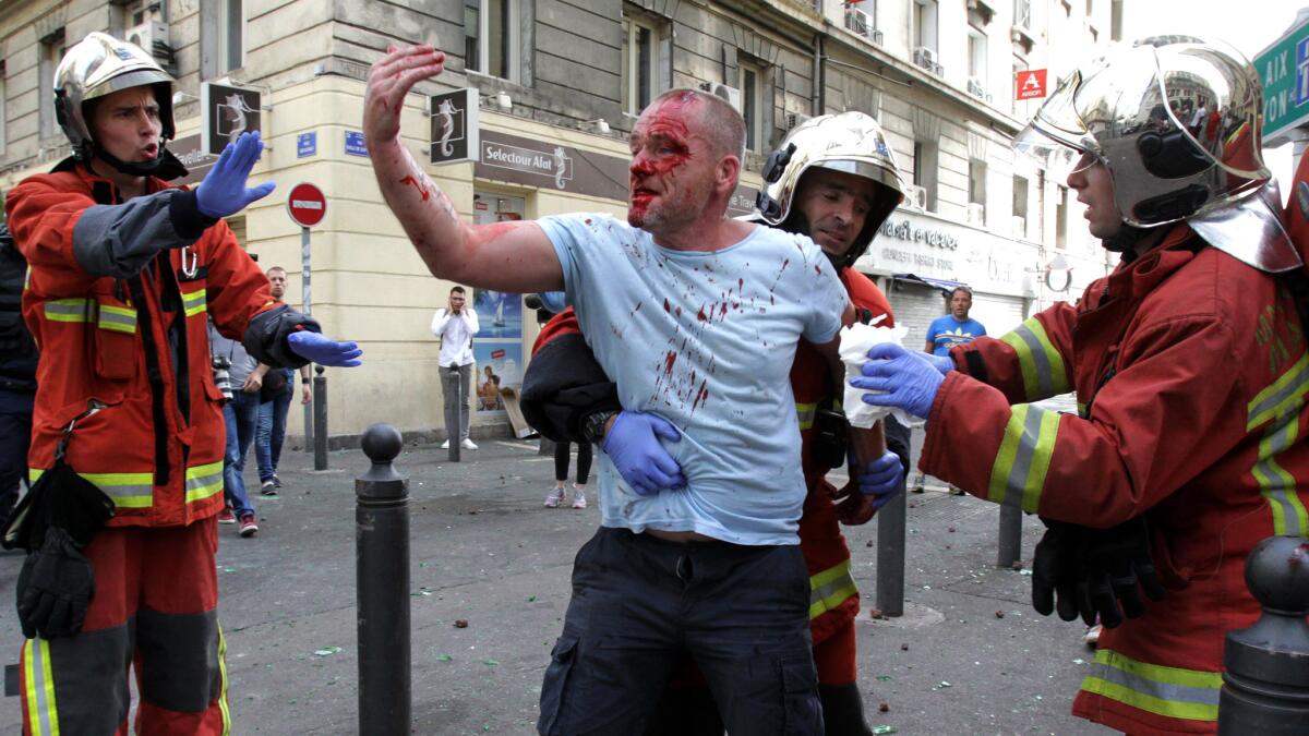 An England supporter injured during a street brawl is helped by a rescue squad in Marseille on Saturday.