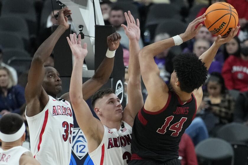Arizona's Christian Koloko (35) and Arizona's Pelle Larsson (3) guard Stanford's Spencer Jones (14) during the second half of an NCAA college basketball game in the quarterfinal round of the Pac-12 tournament Thursday, March 10, 2022, in Las Vegas. (AP Photo/John Locher)
