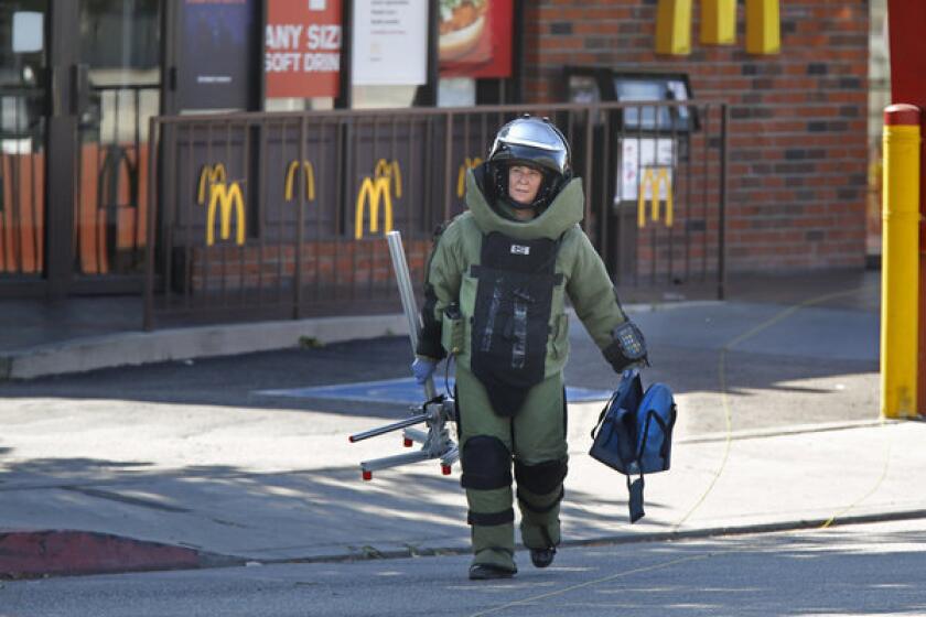 A Los Angeles County Sheriff's Bomb Squad member carries an empty backback from a McDonalds restaurant near the campus of Cal State L.A. on Thursday afternoon.