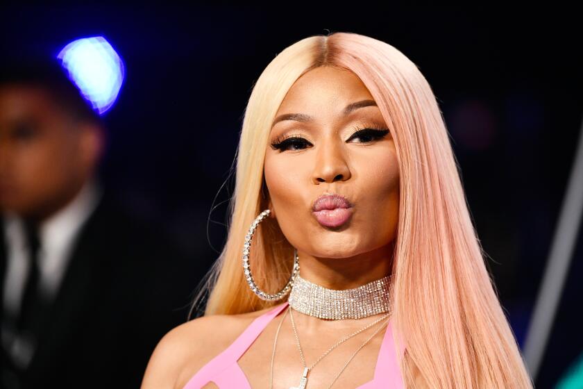 A woman with light blonde and pink hair and hoop earrings  making a kissy face 