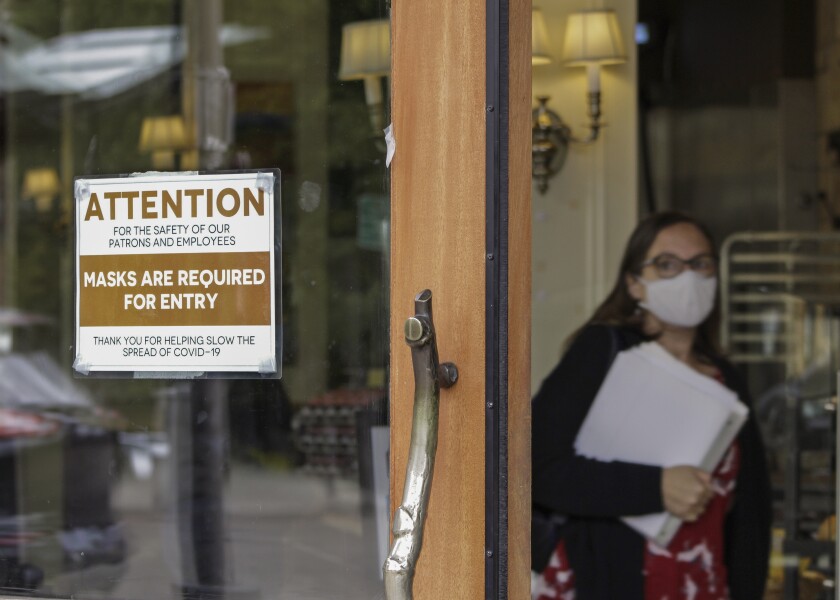 FILE - In this May 21, 2021 file photo, a sign reminds customers to wear their masks at a bakery in Lake Oswego, Ore. Oregon Gov. Kate Brown on Tuesday, Aug. 10, 2021 announced a statewide indoor mask requirement due to the spike in COVID-19 hospitalizations and cases, warning that the state's health care system could be overwhelmed. (AP Photo/Gillian Flaccus, File)