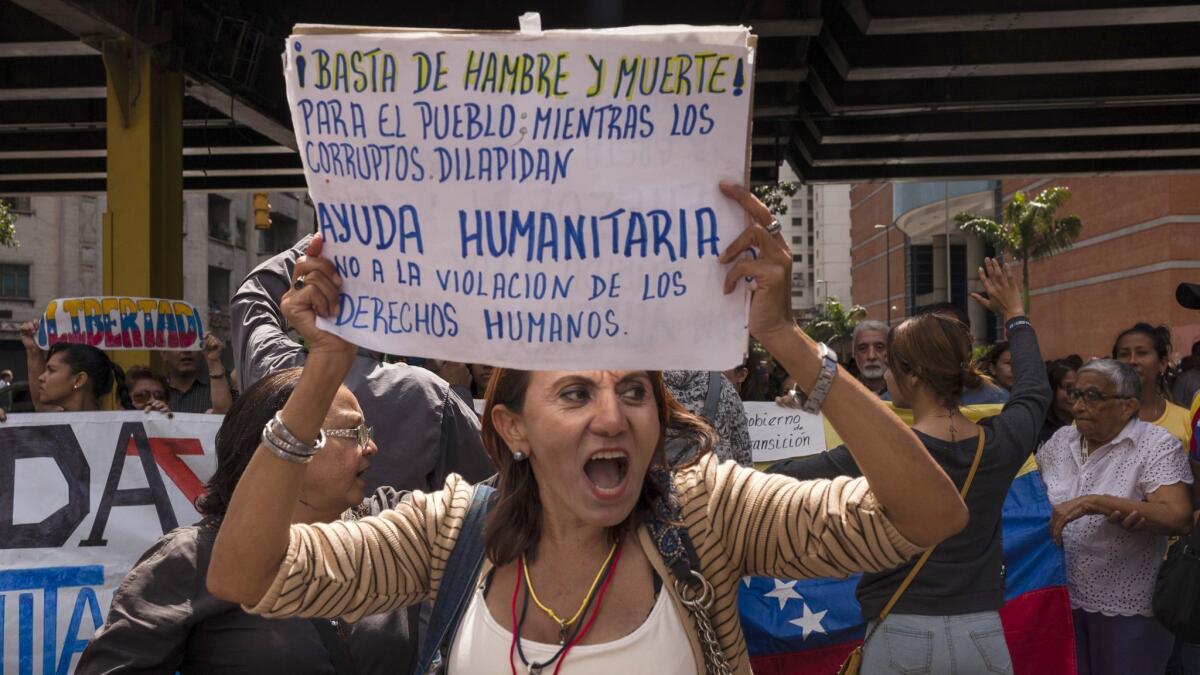 A woman takes part in a protest in Caracas, Venezuela, against the government of President Nicolas Maduro on Wednesday. Her sign reads "Enough with hunger and death for the people, while the the corrupt squander humanitarian aid. No to the violation of human rights."
