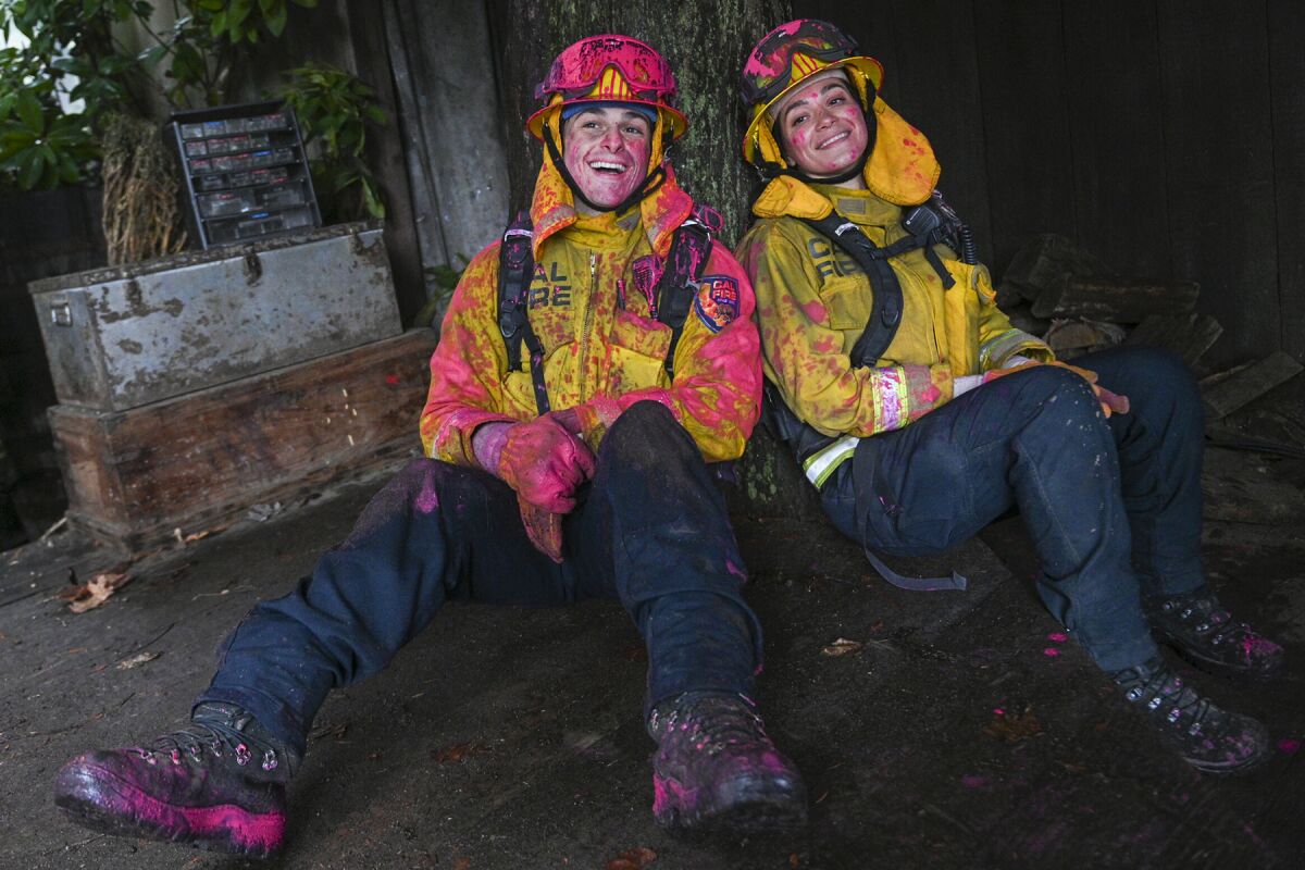 Zach Tinker and Stephanie Arcila sitting on the ground wearing fire fighting gear in "Fire Country" on CBS.