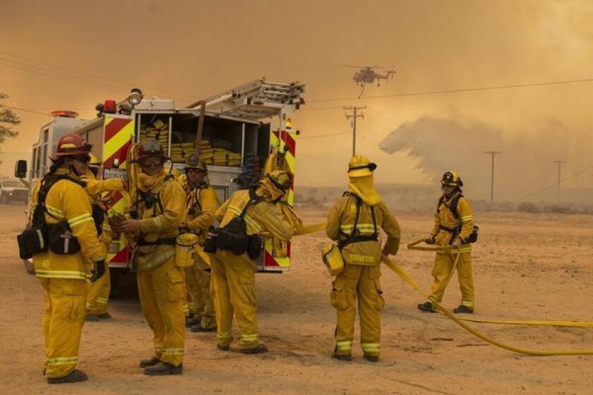 Firefighters prepare to defend a structure while battling the Powerhouse fire near Lancaster.