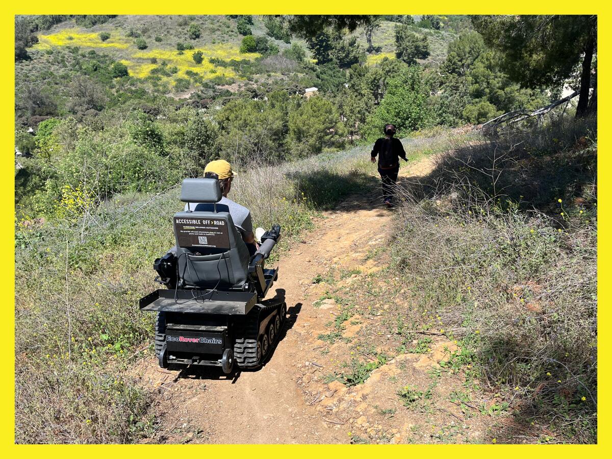 Photo of two people hiking on a trail in southern california. One person in the foreground is in an electric wheelchair.