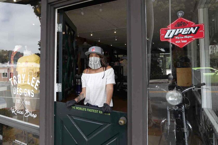 Manager Carmalit Green looks out the door of Troy Lee Designs and Race Shop store in downtown Laguna Beach, as Phase 2 of reopening business in California began on Friday.