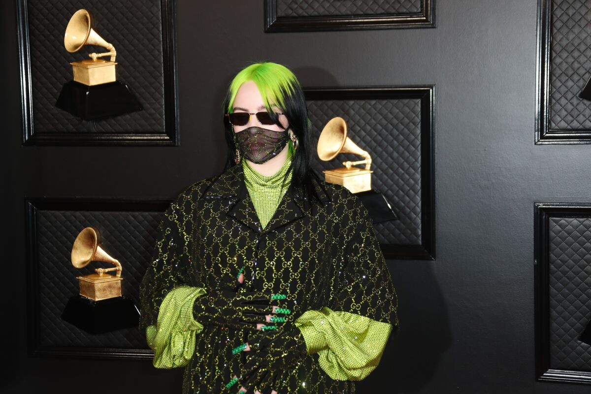 Billie Eilish poses in a lime green and black outfit at the 2020 Grammys.