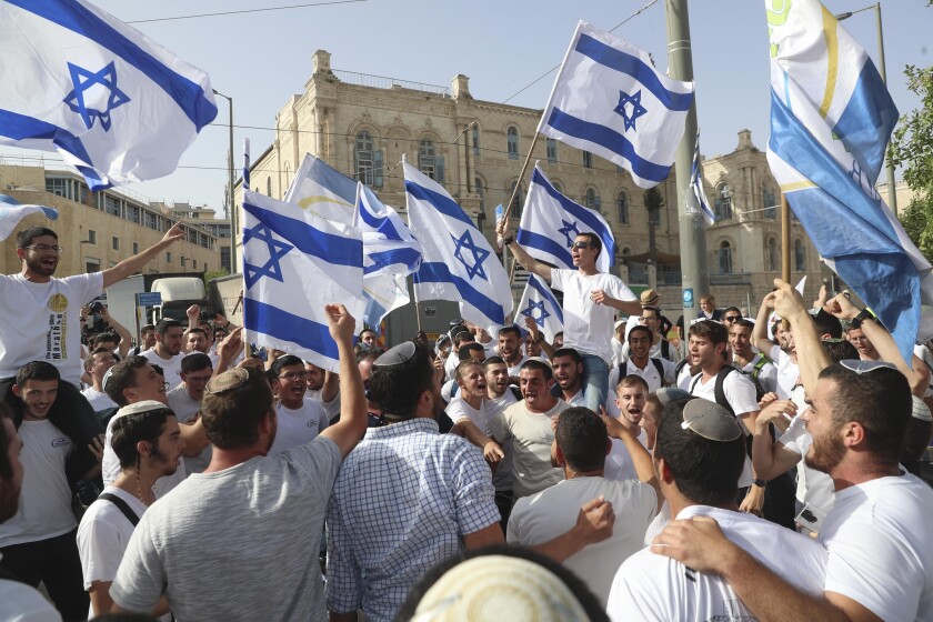 FILE - In this May 10, 2021, file photo, Israelis wave national flags during a Jerusalem Day parade, in Jerusalem. Israel’s new government on Monday, June 14 approved a contentious parade by Israeli nationalists through Palestinian areas around Jerusalem's Old City, setting the stage for possible renewed confrontations just weeks after an 11-day war with Hamas militants in the Gaza Strip. Hamas called on Palestinians to “resist” the march. (AP Photo/Ariel Schalit, File)