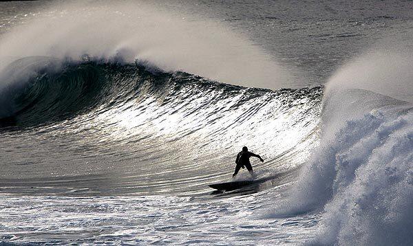 A surfer rides a wave at La Zurriola Beach in Basque Country.