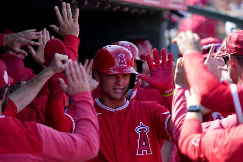 Los Angeles Angels' Logan O'Hoppe high fives teammates after scoring on a base hit by Andrew Velazquez during the fourth inning of a spring training baseball game against the Cleveland Guardians, Monday, March 6, 2023, in Tempe, Ariz. (AP Photo/Matt York)