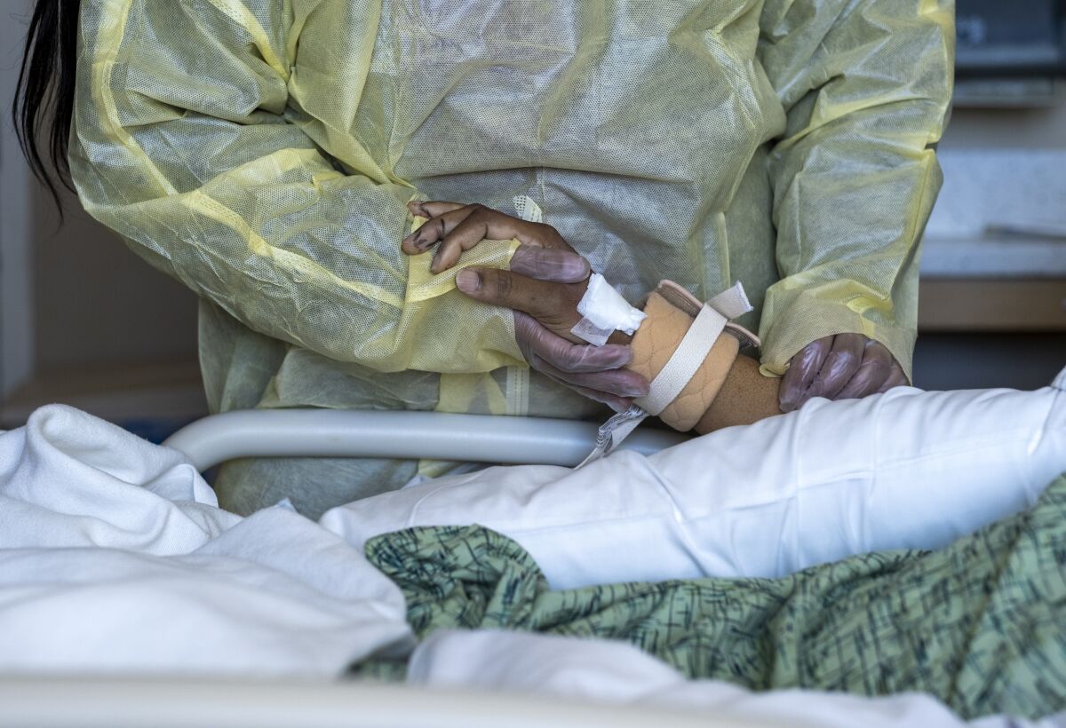 Woman holds her husband's hand in the hospital.