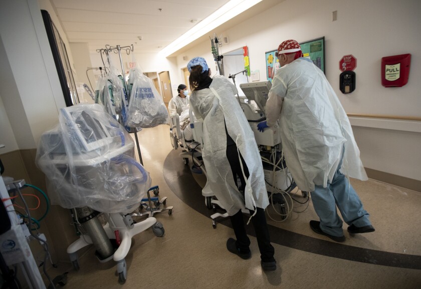 Registered Nurses move a patient last month at the COVID ICU at Providence Holy Cross Medical Center in Mission Hills.