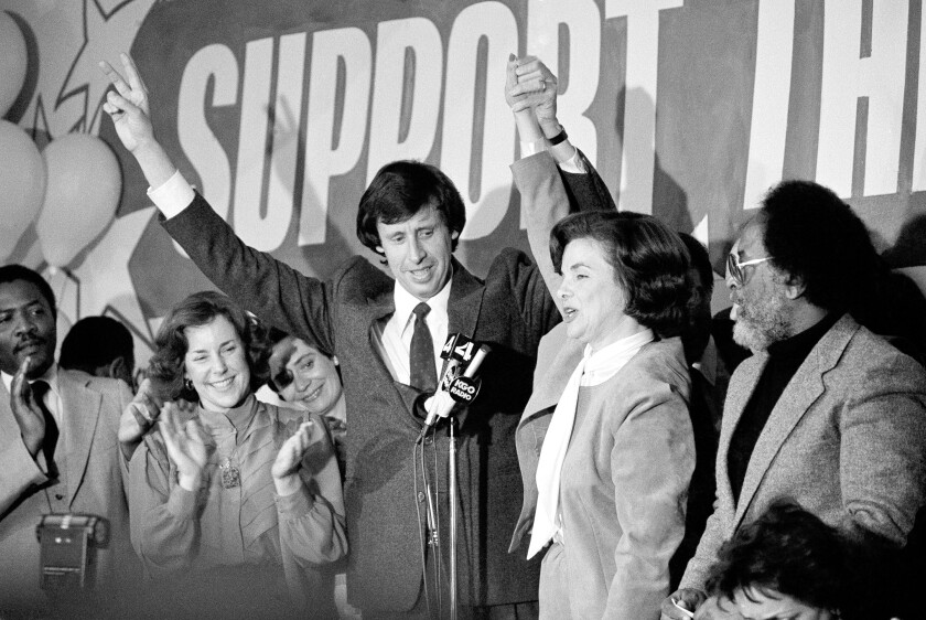 Dick Blum and Dianne Feinstein, arms raised, are surrounded by applauding people.