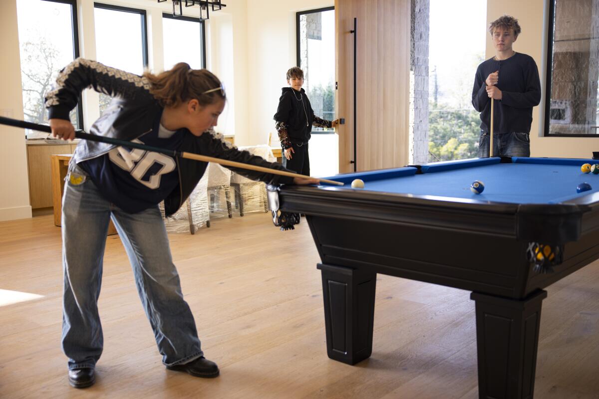 Three people play pool inside their newly rebuilt home in Pacific Palisades