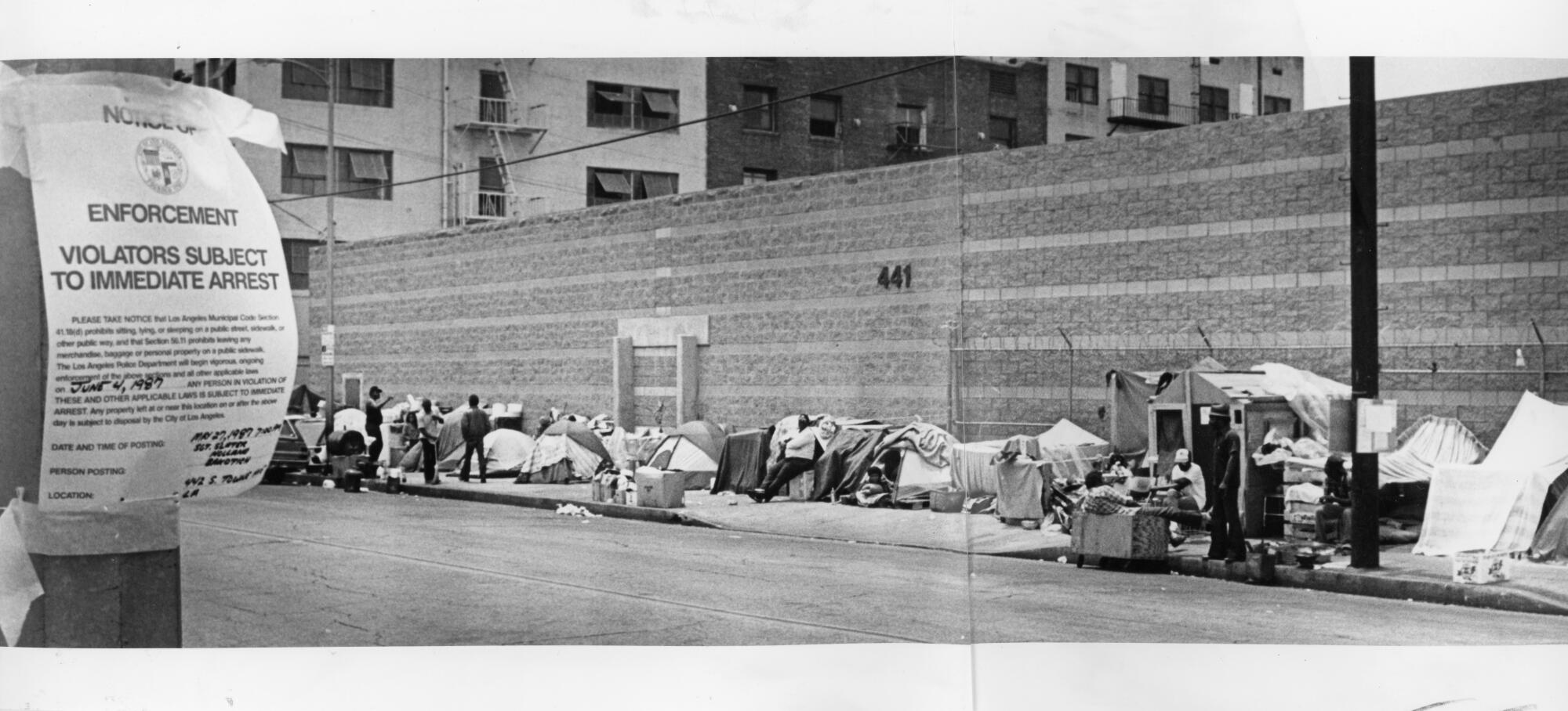 An LAPD sign orders people on Towne Avenue near Fifth Street to get off the sidewalk or face arrest in 1987.