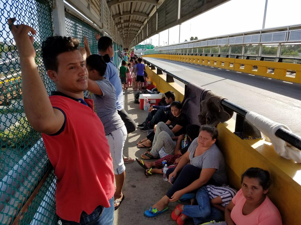 Central American families are camped out on a border bridge between Ciudad Miguel Aleman, Mexico, and Roma, Texas. The man in red in the foreground is Marco Estrada from Honduras.