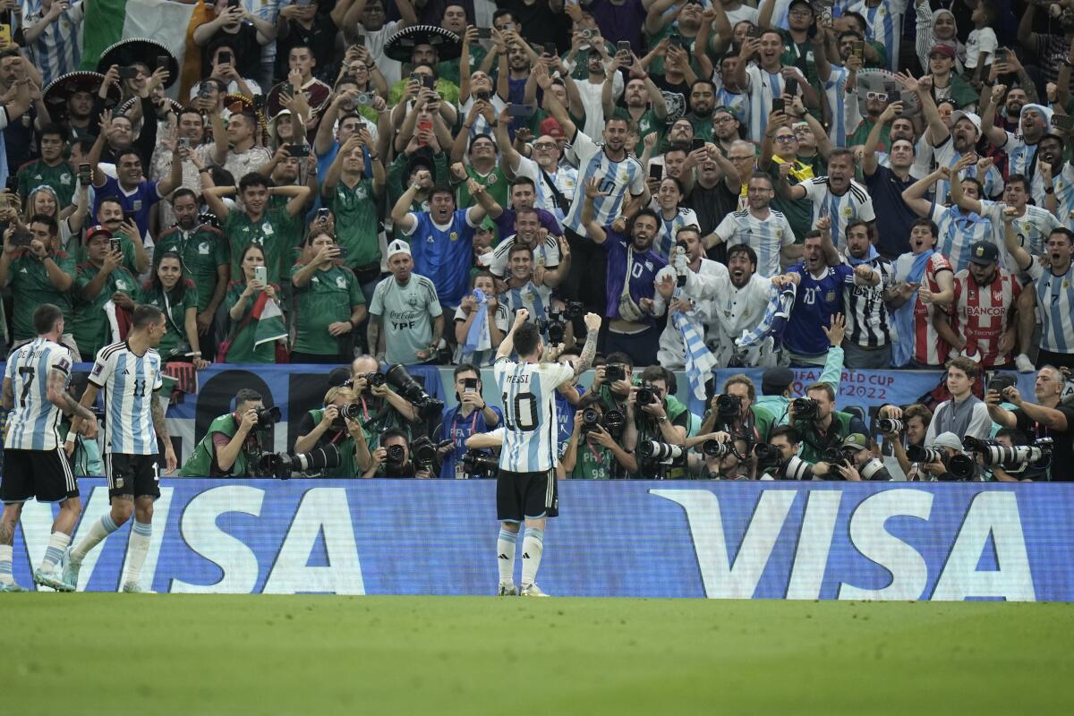 Lionel Messi raises his arms toward fans at the World Cup.