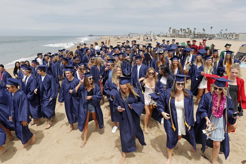 Newport Mesa Unified District seniors walk along the coast as they make their way from Newport Elementary School to Balboa Pier in Newport Beach on Friday.