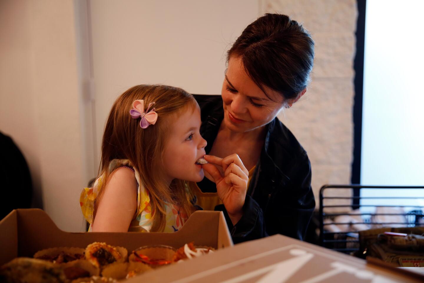 Kristen Olsen feeds her daughter Olivia Stouffer a pastry.