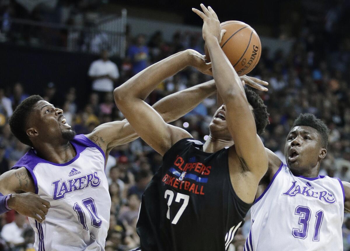 Los Angeles Lakers' David Nwaba, left, and Thomas Bryant, right, guard Los Angeles Clippers' Isaiah Hicks during the first half of an NBA summer league basketball game on July 7, 2017, in Las Vegas.