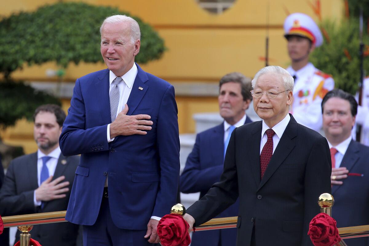 Biden stands with his hand over his heart at a welcome ceremony in Vietnam.