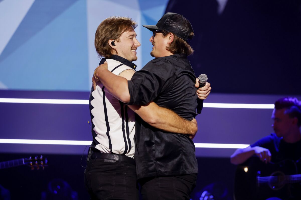Two musicians hug onstage