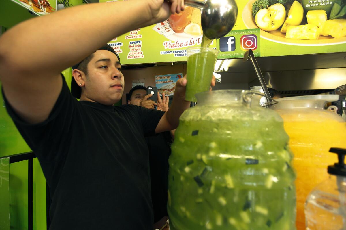 Randy Peña, 14, pours a juice for a customer. (Kirk McKoy / Los Angeles Times)