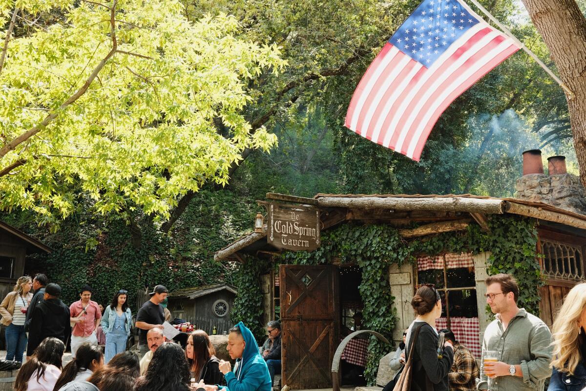 A crowd outside of Cold Spring Tavern. At right, an American flag waves.