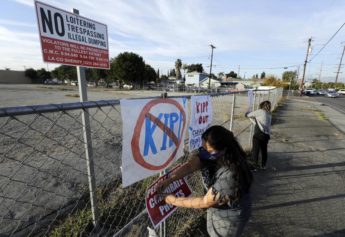 A teacher attaches a sign to a fence to oppose a proposed charter school.