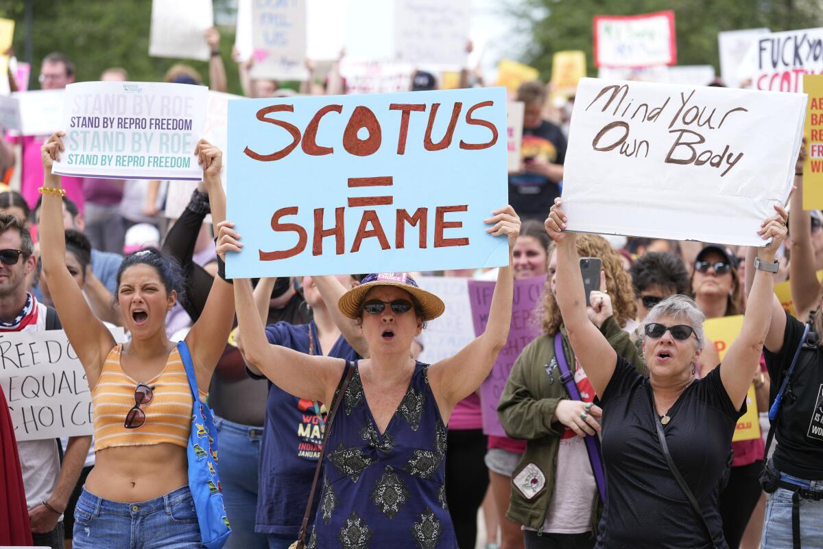 Abortion rights activists hold signs and chant at a rally