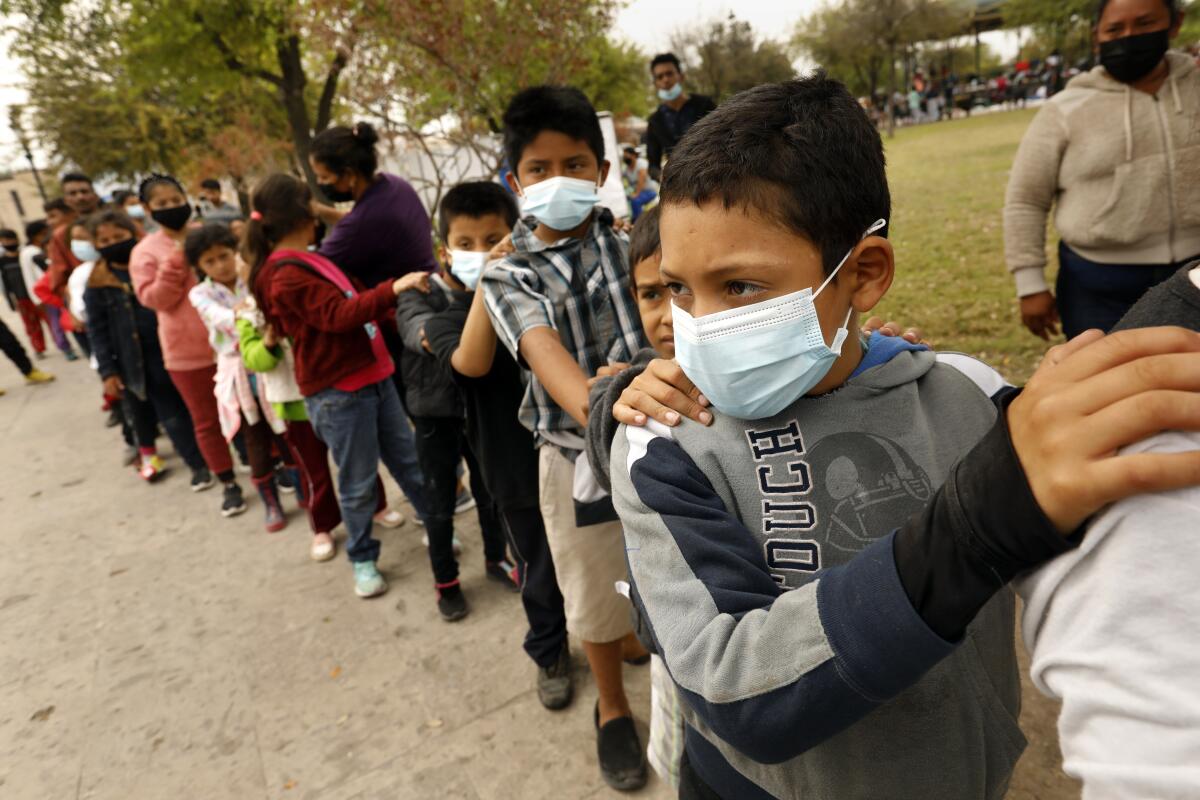 Children wait in a line outdoors. 