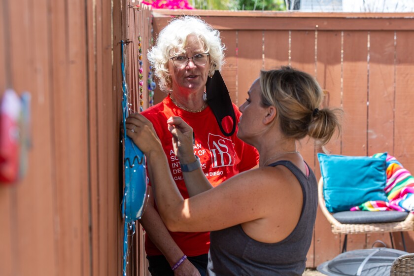 ASID designer Beppie Mostert and Humble designer Amber Courtney pin decorations on the backyard fence of the Ibarras’ home.