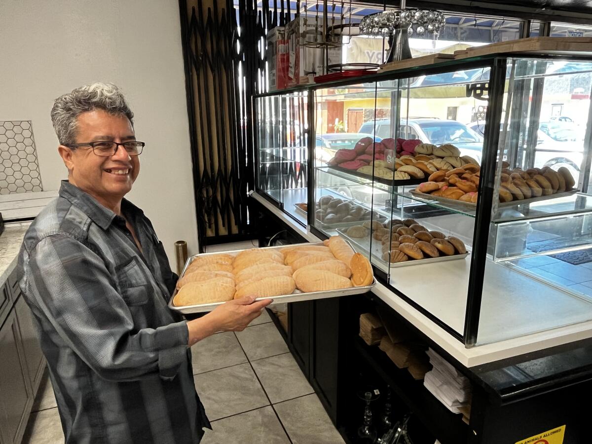 Soy Concha Bakery employee Don Adolfo Farias shelves a tray maiz-shaped bread known as elotes. 