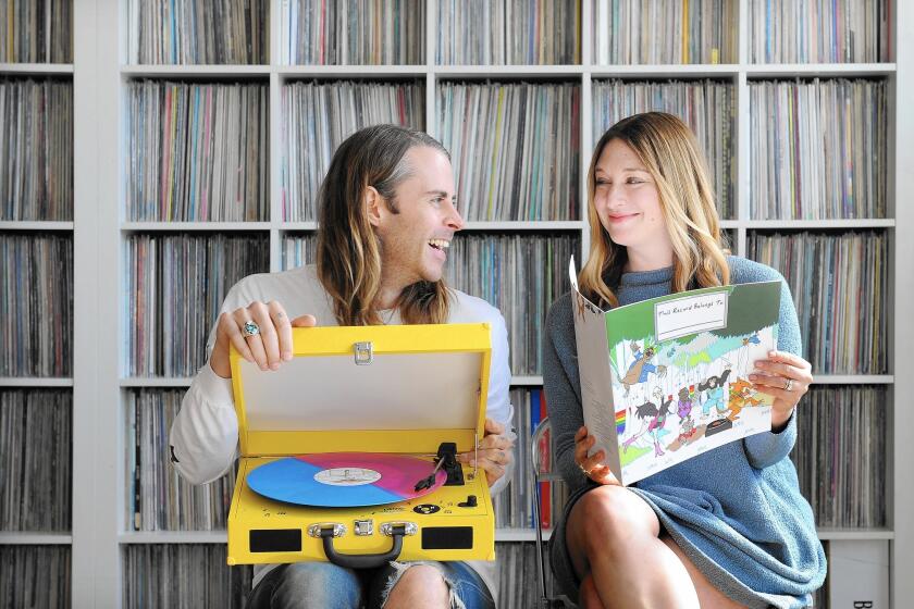 DJ Zach Cowie and artist Jessica Rotter hold their "This Record Belongs To ..." album, turntable and book set.