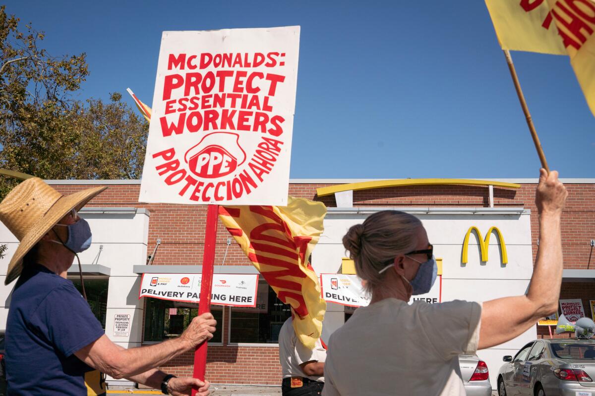 David White, 77, and Rande Webster, 72, support protesters during a strike to protect essential workers at McDonald's 