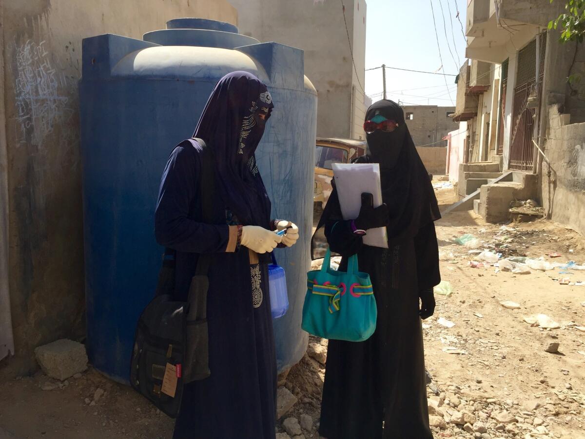 Saira Nizamuddin, right, confers with a fellow polio vaccinator. (Shashank Bengali / Los Angeles Times)