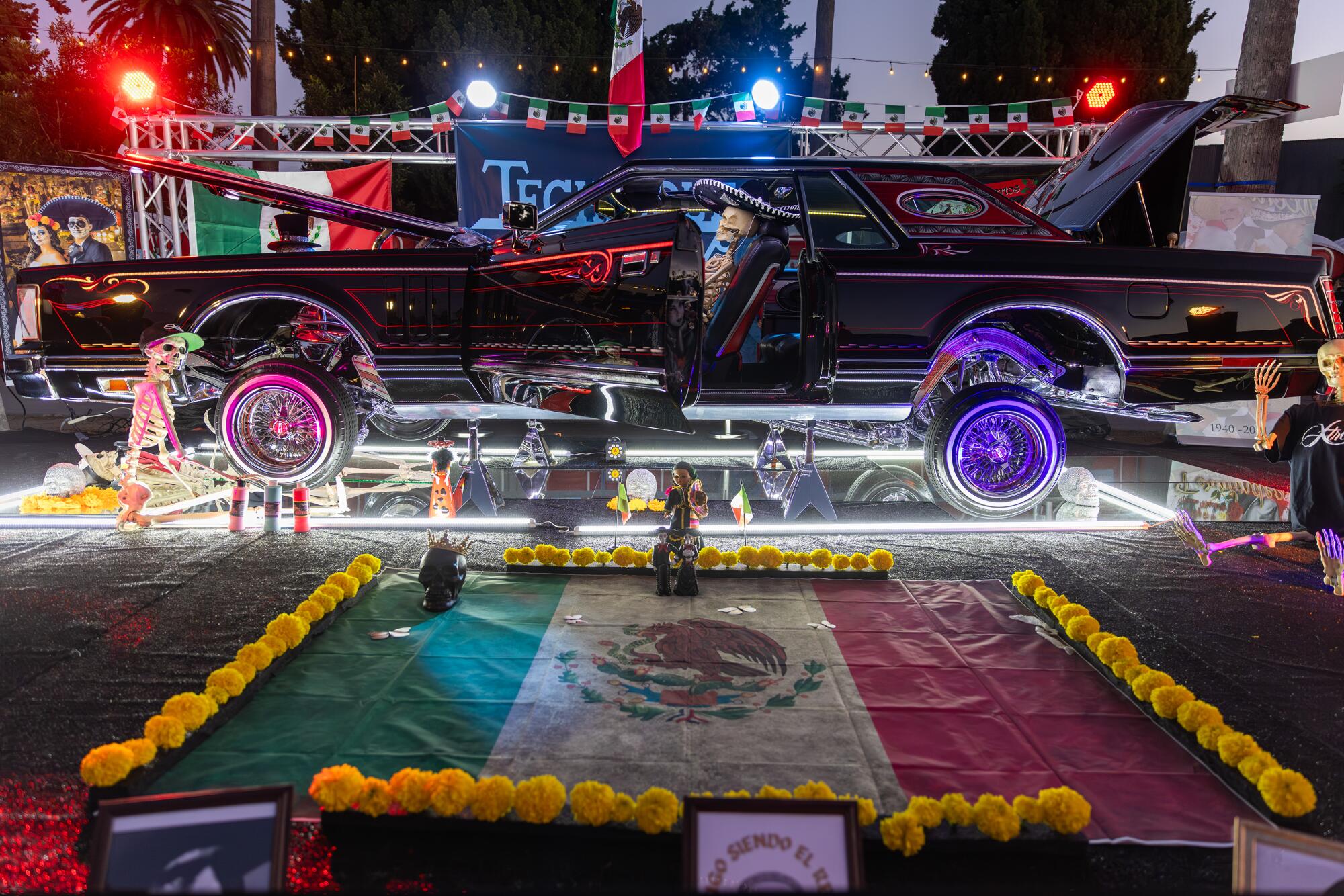 An altar with a black car above and yellow flowers around the Mexican flag on display at the Hollywood Forever Cemetery.