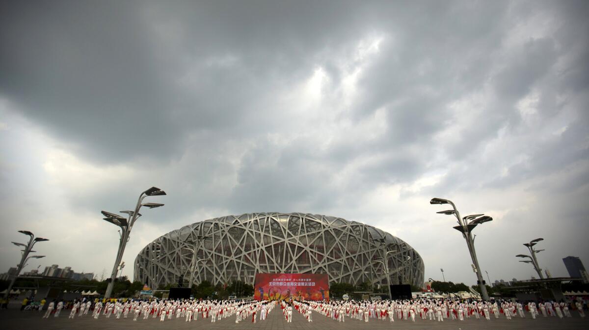 Participants dance under threatening skies at a gathering to watch the announcement of the 2022 Winter Olympics host city outside the Beijing Olympic Stadium, also known as the Birds Nest on Friday.