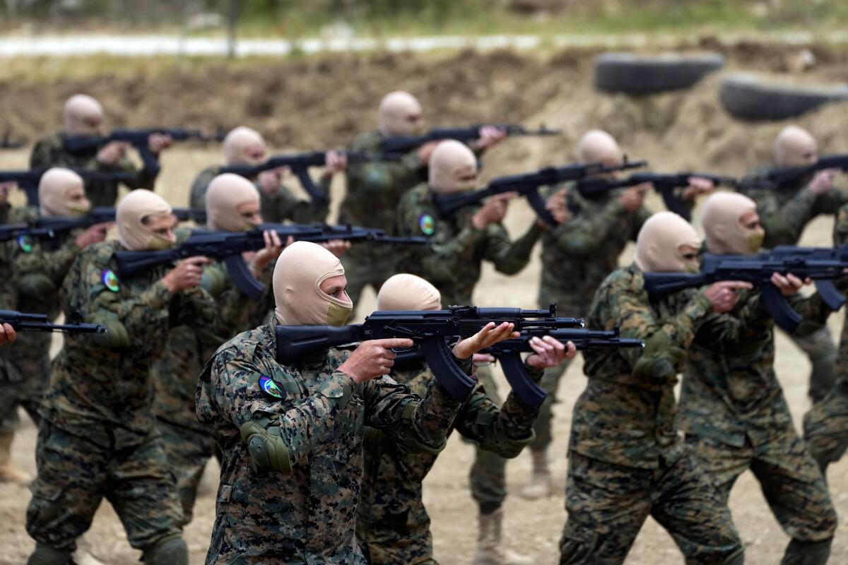 Masked militia members train with weapons.