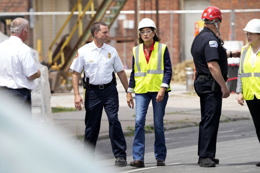 Iowa Gov. Kim Reynolds, center, talks with local officials while touring the site of an apartment building collapse, Monday, June 5, 2023, in Davenport, Iowa. The six-story, 80-unit building partially collapsed May 28. (AP Photo/Charlie Neibergall)