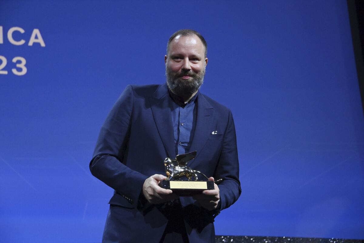 A man in a blue suit holding an award.