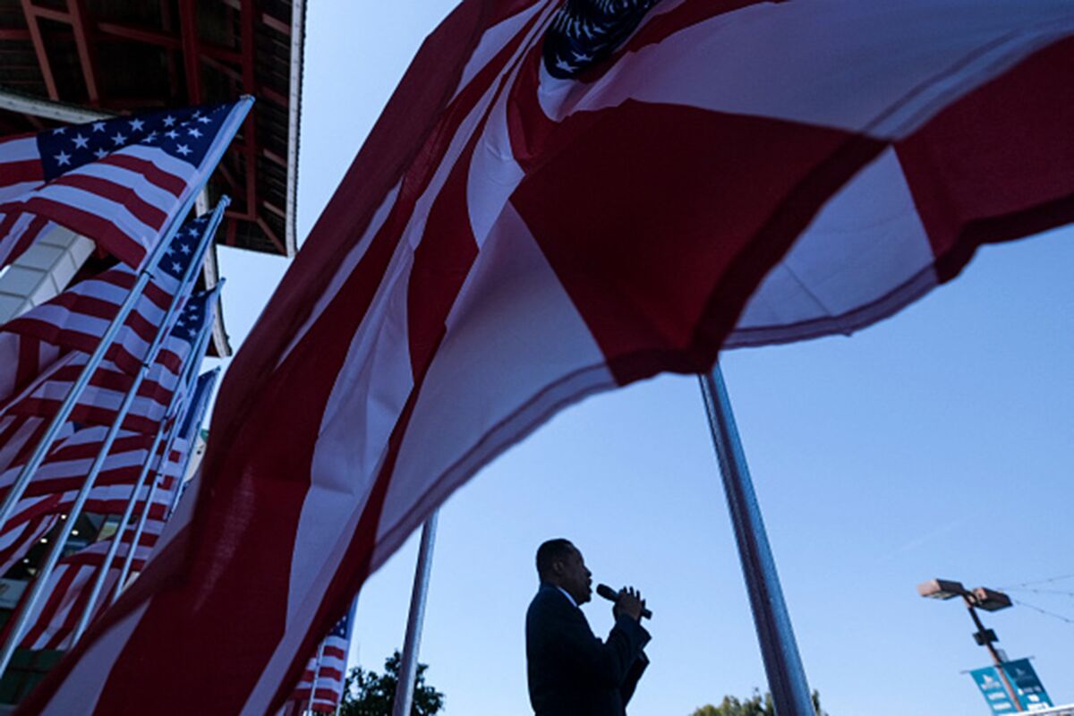 Larry Elder speaks into a microphone near American flags