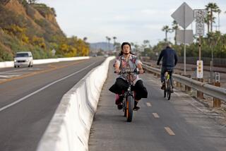 CAPISTRANO BEACH, CA - JANUARY 12: A person, left, on an electric bike (e-bike), next to a person on a conventional bike, rides the coastal bike trail along the 34800 block of Pacific Coast HWY on Thursday, Jan. 12, 2023 in Capistrano Beach, CA. Orange County cities attempting to regulate electric bikes (e-bikes) with varying degrees of success. (Gary Coronado / Los Angeles Times)