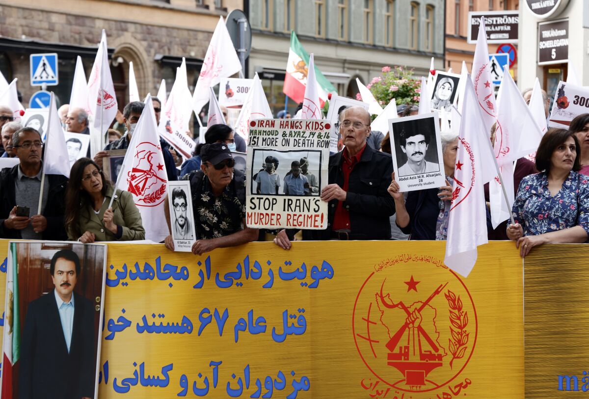 Supporters of the People's Mojahedin Organization of Iran protest outside Stockholm's district court on the first day of the trial of Hamid Noury, in Stockholm, Tuesday, Aug. 10, 2021. An Iranian man is standing trial in Sweden charged with grave war crimes and murder during the final phase of the Iran-Iraq war in the 1980s. The trial of Hamid Nouri comes just days after Iran's hard-line President Ebrahim Raisi took office as the highest-ranking civilian leader in the Islamic Republic. (Stefan Jerrevang/TT News Agency via AP)