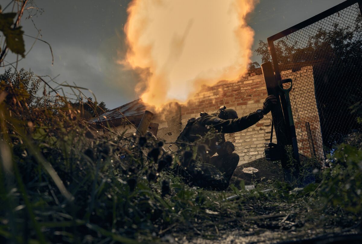 As a soldier crouches, Ukrainian soldiers open fire in Kupiansk.