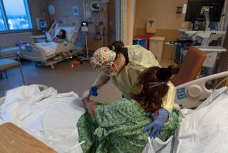 Registered nurse a COVID-19 patient helps a patient at Providence Holy Cross Medical Center in Los Angeles, on Dec. 13, 2021.