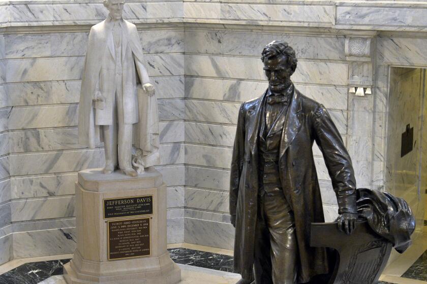 FILE - In this Aug. 5, 2015 file photo, a statue of Jefferson Davis, left, faces a statue of Abraham Lincoln in the Rotunda of the state Capitol in Frankfort, Ky. The statues tower over visitors to Kentucky's Capitol, but the state's governor doesn't think the Confederate president belongs in the same space as the U.S. president who helped end slavery. Democratic Gov. Andy Beshear said Thursday, June 4, 2020 that he sees the Davis statue as a divisive symbol that should be removed from the Capitol Rotunda. (AP Photo/Timothy D. Easley, File)